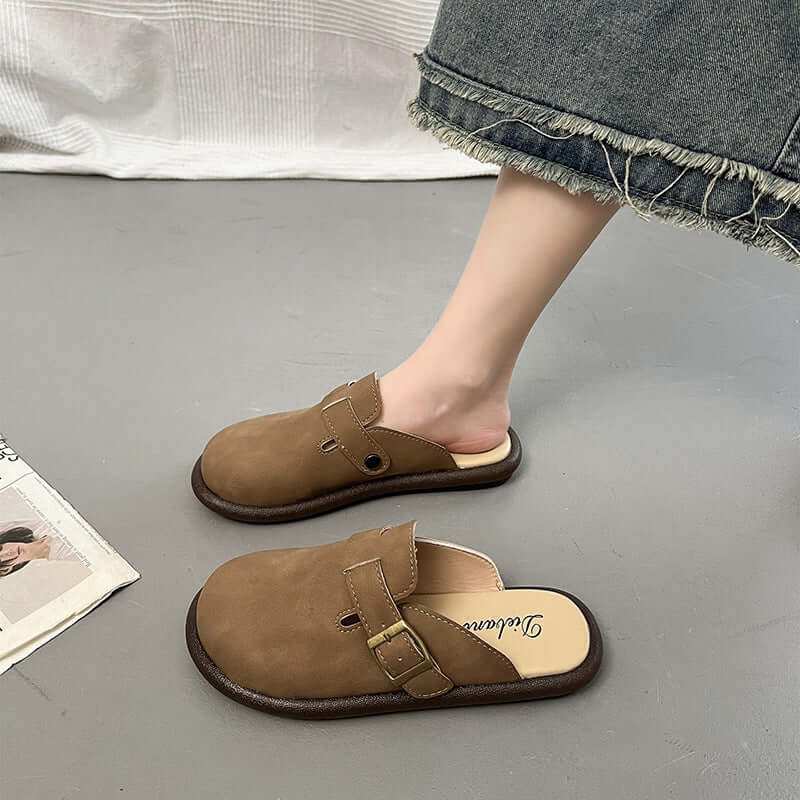 Women's suede round toe slip-ons, brown flats on a person wearing a denim skirt.