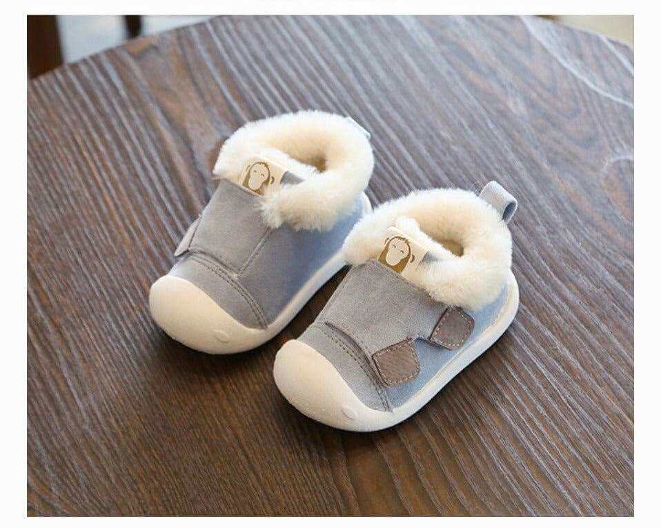 Velvet and cotton toddler shoes with non-slip soles on wooden surface.