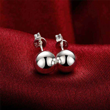 Creative 6M 8M 10M Bead Stud Earrings in silver on red fabric backdrop.