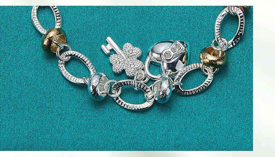 Silver Love Key Bracelet with retro ethnic design and love-shaped charm on teal background.