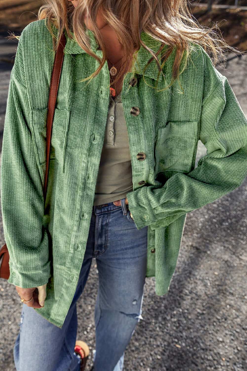 Pocketed collared neck button up shacket in green on a person outdoors.