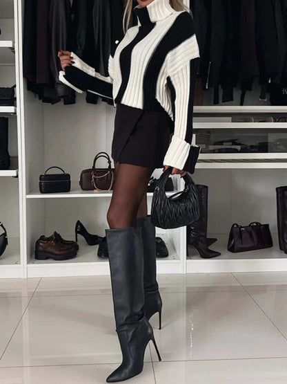 Striped turtleneck dropped shoulder sweater in black and white worn with knee-high boots.