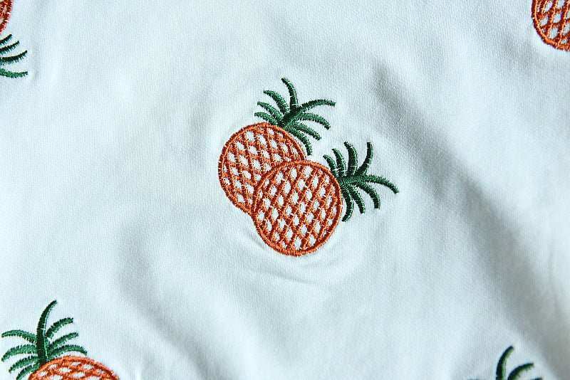 Embroidered sweater fabric detail with pineapple pattern.