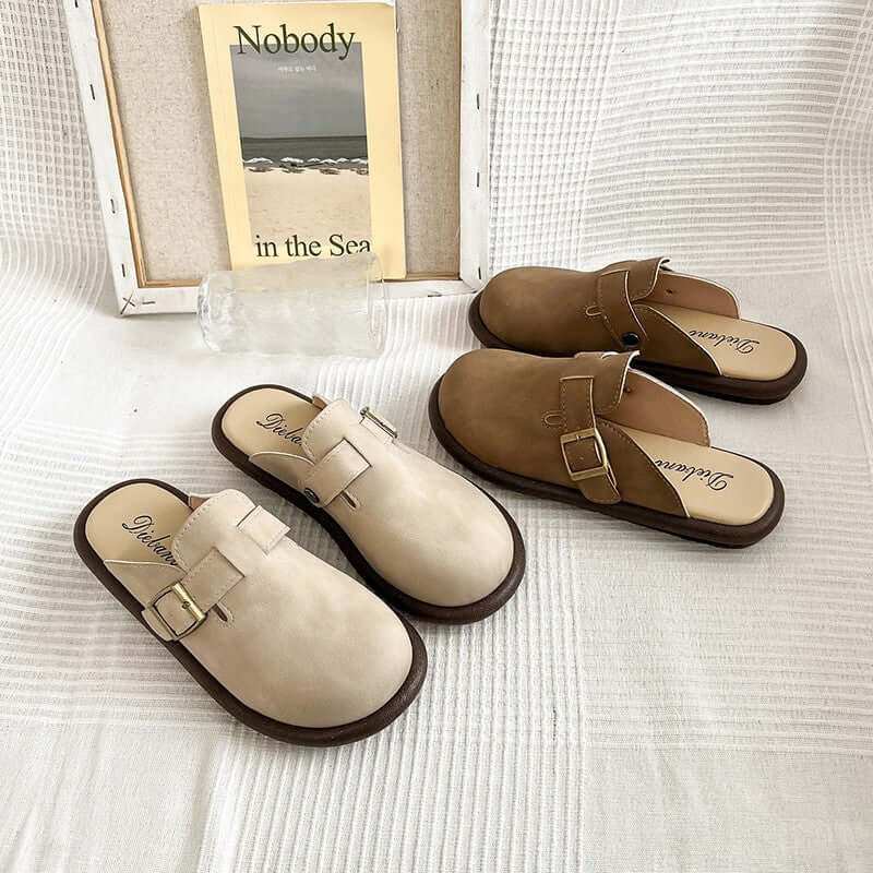 Suede round toe slip-ons for women in beige and brown with buckle detail displayed on white fabric.