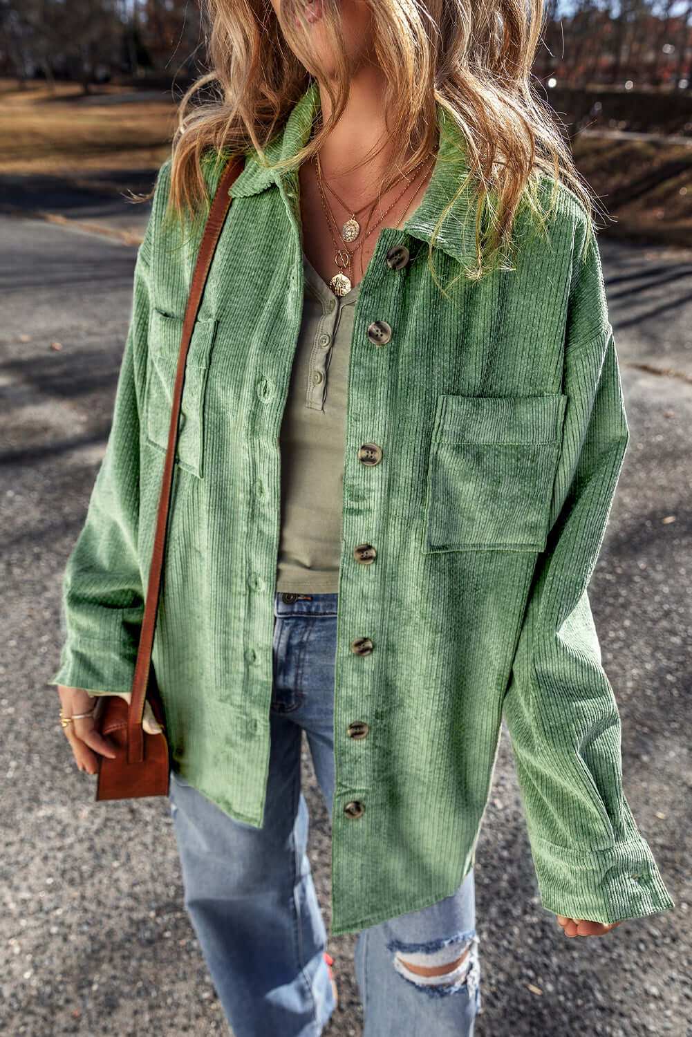 Pocketed collared neck button up shacket in green worn outdoors.