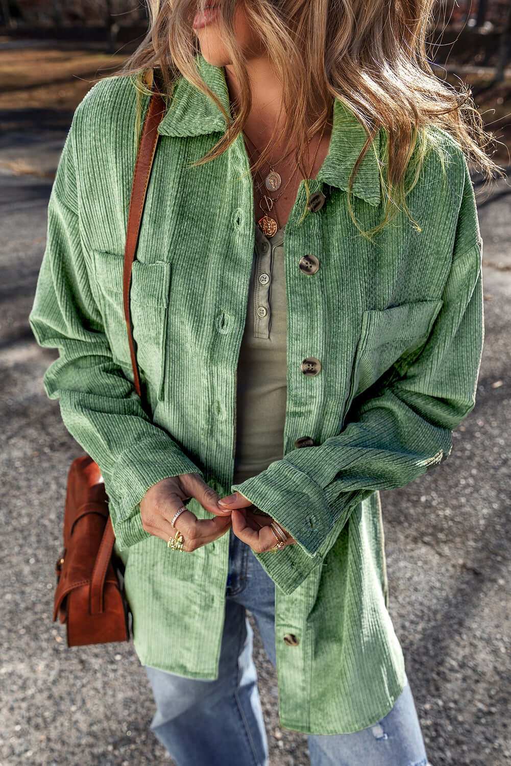 Pocketed collared neck button up shacket in green worn outdoors.